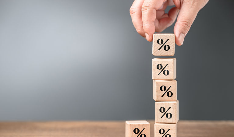 Closeup hand stack up the wood cubes with percentage symbol, mathematics, commission, or compound interest concept