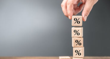 Closeup hand stack up the wood cubes with percentage symbol, mathematics, commission, or compound interest concept