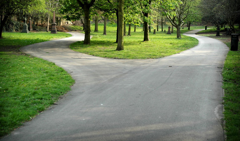Forked road in St. James Gardens, Liverpool. St James's Cemetery is an urban park behind the Liverpool Cathedral. This photo symbolise a choice between two different paths. Diminishing perspective point of view..