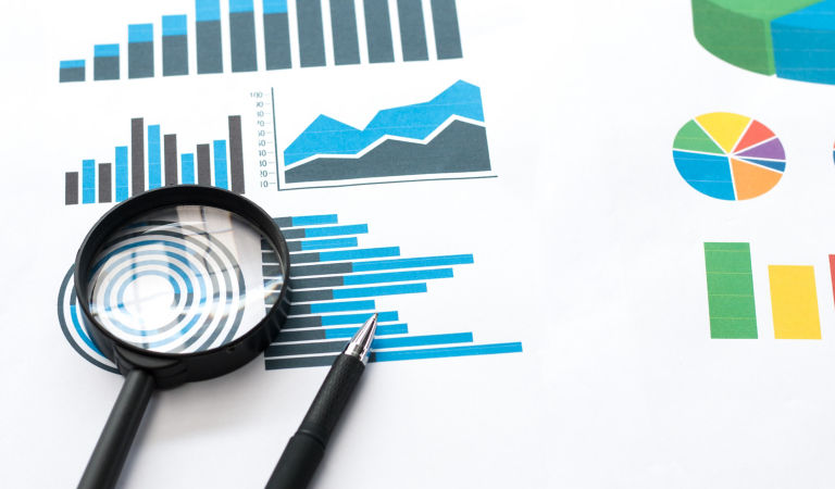 Papers with business report and magnifying glass