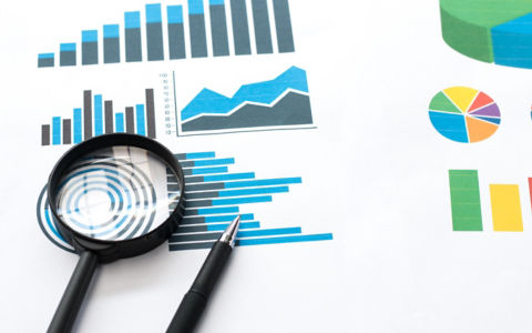 Papers with business report and magnifying glass