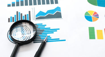 Papers with business report and magnifying glass