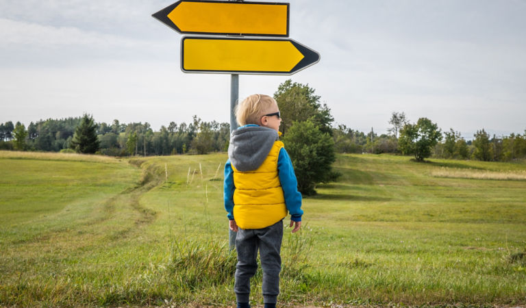 Little boy looking for road direction on a beautiful green plateau. Slovenia, Europe.