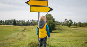 Little boy looking for road direction on a beautiful green plateau. Slovenia, Europe.